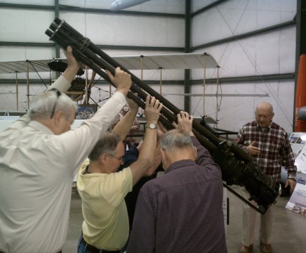 Directed by Dave Seeman, right, a group of Patuxent River Naval Air Museum volunteers shift an aircraft gatling gun to make space for a new display.