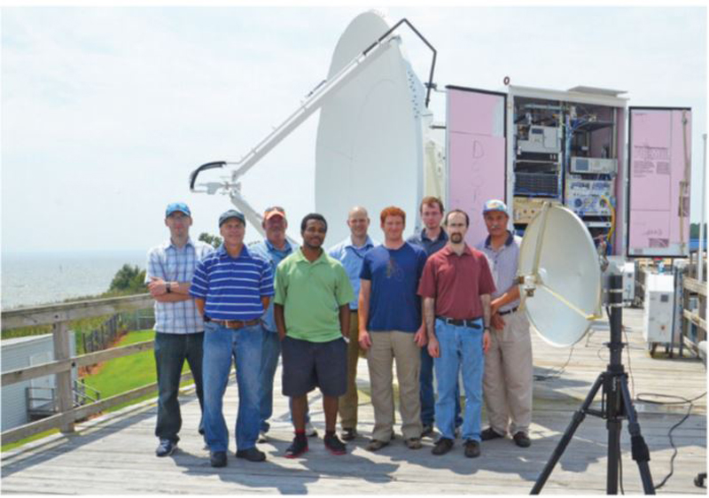 In August 2015, personnel from Lincoln Laboratory and the Atlantic Test Range demonstrated the laboratory’s wind turbine interference-mitigation approach. Various hardware components were integrated into the ADAMS X-band system. An auxiliary parabolic reflector antenna (small antenna in the foreground) was utilized to show the effectiveness of spatial mitigation techniques. An arbitrary waveform generator, stored in the cabinet shown in the background, was used to exhibit the utility of pulse-compression and pulse-to-pulse techniques.
